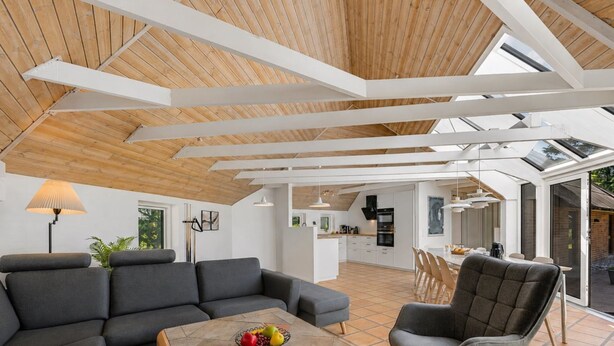 Ein modernes Interieur mit Holzbalkendecke, einem Essbereich und einer Küche.