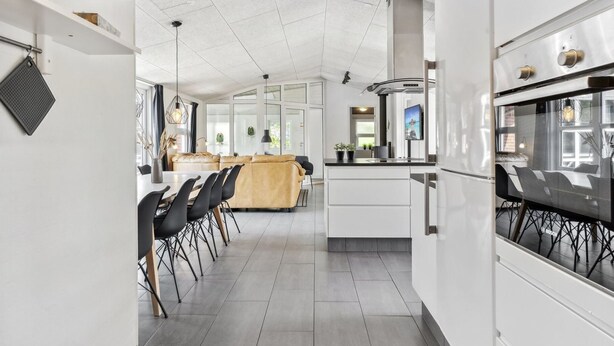 A modern kitchen with white cabinetry, a central island, and a dining area with black chairs. - "Jonke" - 800m from the sea by Interhome (Blåvand)