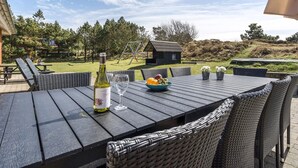 An outdoor dining area with a table set for two, a bottle of wine, and a bowl of fruit. - "Jonke" - 800m from the sea by Interhome (Blåvand)