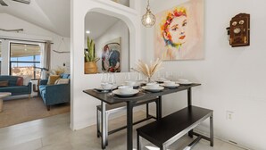 A dining area with a dark wooden table set for four, a bench, and a painting on the wall. - Summer Relax & Unwind @ Genesis Oasis - Wifi + Spa! Pet Friendly! (Joshua Tree)