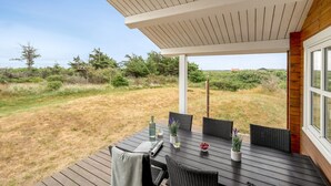 Un patio al aire libre con una mesa y sillas, rodeado por un paisaje natural.
