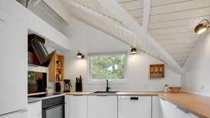 Ett modernt kök med vita skåp, en inbyggd ugn och ett fönster som släpper in naturligt ljus.