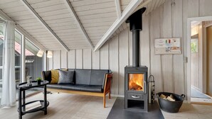 Ett mysigt rum med en svart soffa, ett litet bord och en vedeldad kamin.