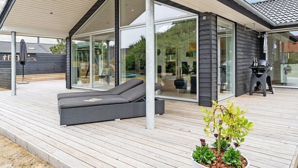 Une terrasse extérieure moderne, dotée d’une enceinte en verre, d’un espace détente et d’un barbecue.