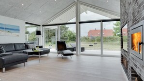 Un salon moderne avec une cheminée, un canapé, un fauteuil et une table basse.