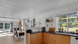 A modern kitchen with wooden cabinets, a black countertop, and a large window offering a view of greenery. - "Harpa" - 2.5km from the sea by Interhome (Blåvand)