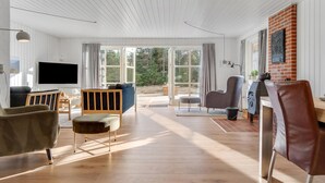 A spacious living room with a large TV, wooden flooring, and a view of the outdoors. - "Harpa" - 2.5km from the sea by Interhome (Blåvand)