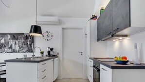 A modern kitchen with white cabinetry, a black pendant light, a coffee machine, and a fruit bowl on the counter. - "Todorka" - 800m from the sea by Interhome (Blåvand)