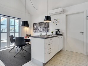 Een moderne keuken met een groot eiland, hanglampen, een koffieapparaat en een kunstwerk van een stadsgezicht.