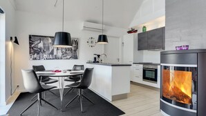 A modern kitchen with a central island, a dining area with a table and chairs, and a large fireplace. - "Todorka" - 800m from the sea by Interhome (Blåvand)