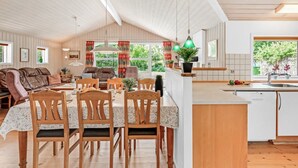 Un vaste espace de vie doté d’un haut plafond, une table à manger avec des chaises, un canapé et un coin cuisine avec un évier et un plan de travail.