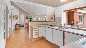 Une cuisine moderne avec des meubles blancs, un plan de travail en bois et un mur en briques.