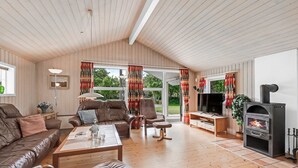 Un salon spacieux doté d’un parquet, de meubles en cuir, d’une cheminée et de grandes fenêtres.