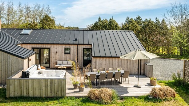 A modern house with a deck, outdoor seating, and a hot tub. - "Gunny" - 500m to the fjord by Interhome (Blåvand)