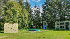 A playground with a climbing wall, swing set, slide, and a small playhouse. - "Patrik" - 1.4km from the sea by Interhome (Blåvand)