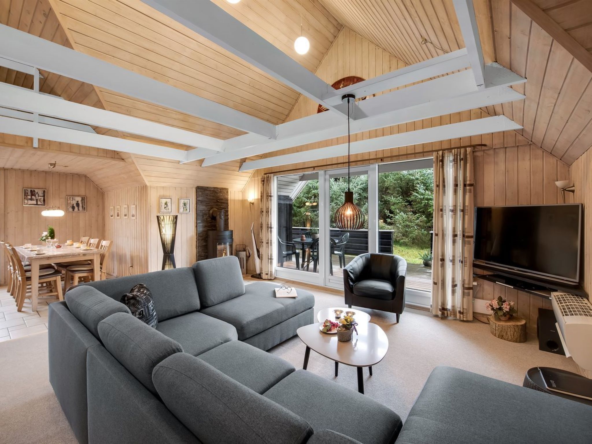 A modern living room with a sectional sofa, a flat-screen TV, and a dining area with a table and chairs.