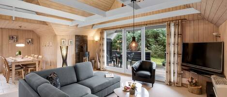A modern living room with a sectional sofa, a flat-screen TV, and a dining area with a table and chairs.