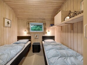 A cabin room with two beds, a window, a wall-mounted clock, and a bicycle rack.