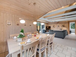 Een houten interieur met een eethoek, een bank en een televisie.