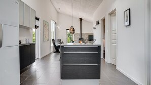 A modern kitchen with a central island, white cabinetry, and a large window providing natural light. - "Siegfried" - 500m from the sea by Interhome (Blåvand)