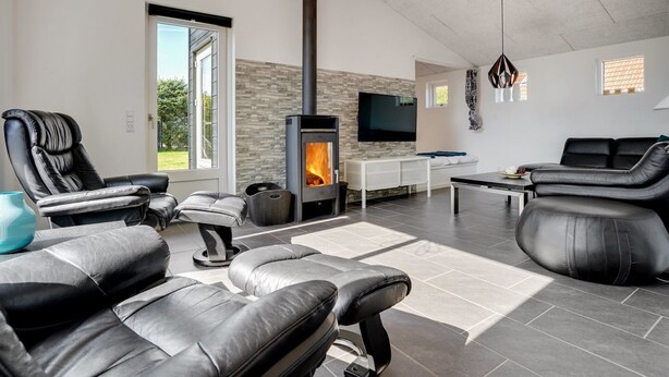 A modern living room with leather sofas, a fireplace, a TV, and a stone wall. - "Siegfried" - 500m from the sea by Interhome (Blåvand)