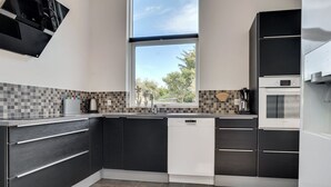 A modern kitchen with dark cabinetry, a dishwasher, and a window providing a view of the outdoors. - "Siegfried" - 500m from the sea by Interhome (Blåvand)
