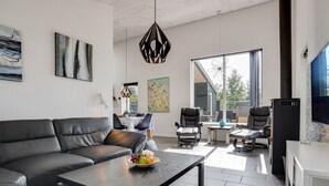 A modern living room with a black leather sofa, a wooden coffee table with fruit, and a dining area with a table and chairs. - "Siegfried" - 500m from the sea by Interhome (Blåvand)