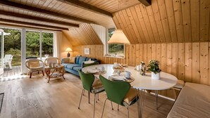 A cozy, wooden interior with a dining area, a sofa, and a table set for a meal.