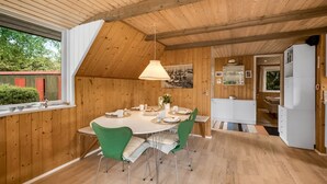A cozy kitchen with wooden walls, a dining table with chairs, and a hanging light fixture.