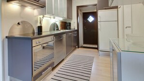 Una cocina moderna con electrodomésticos de acero inoxidable, horno empotrado y una mesa de comedor de vidrio.