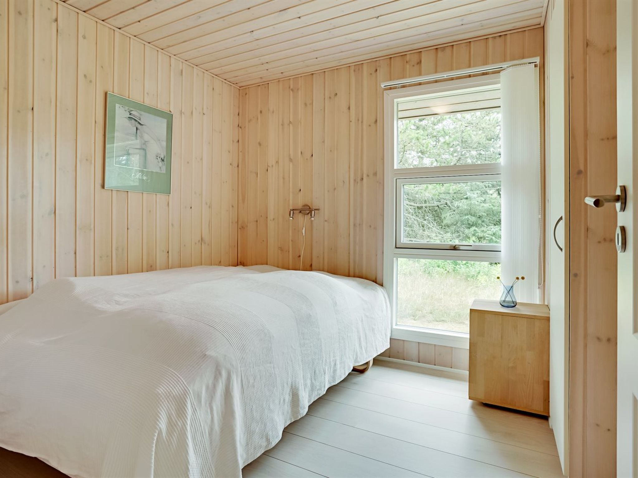A bedroom with a bed, a window, and a door.
