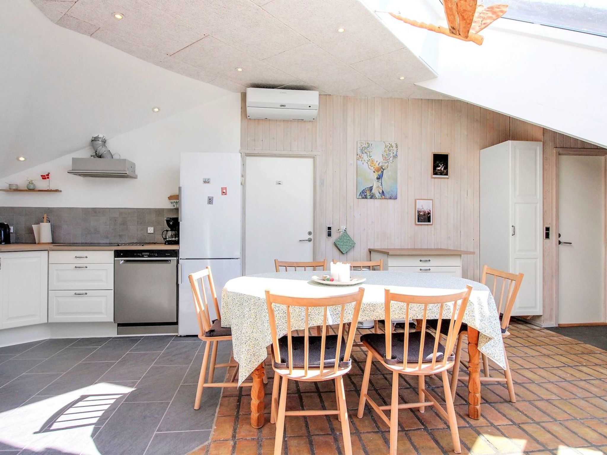 Une cuisine moderne avec des meubles blancs, un four encastré et un coin repas comprenant une table et des chaises.