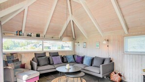 A cozy living room with a large sectional sofa, a small round table, and a window overlooking a residential area.