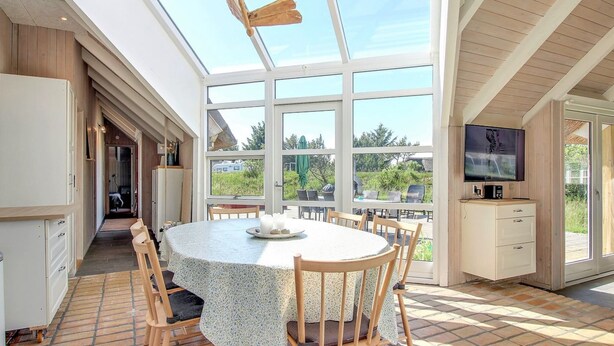 A dining area with a round table, chairs, and a TV on a cabinet.