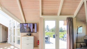 A room with a television mounted on a wall, a sliding glass door leading to an outdoor patio, and a seating area with a sofa and a table.