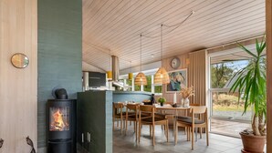 A modern kitchen with a wood-burning stove, dining area with wooden chairs, and a large window. - "Birgita" - 700m from the sea by Interhome (Vejers Strand)