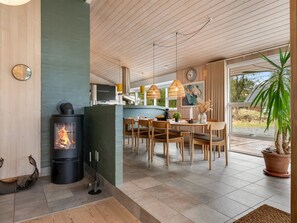 Eine moderne Küche mit Kaminofen, Essbereich mit Holzsesseln und einem großen Fenster.