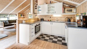A modern kitchen with white cabinets, a stainless steel range hood, and a microwave.