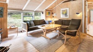 A cozy, wooden interior with a sofa, armchairs, and a table.