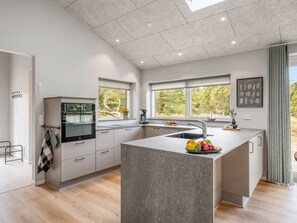 A modern kitchen with a central island, built-in oven, and large windows.
