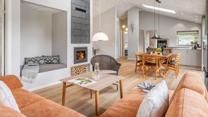 Uma sala de estar moderna com lareira, área de jantar e cozinha.