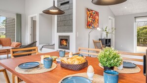 Uma sala de jantar com uma mesa de madeira, pratos azuis e uma lareira.