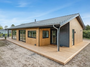 A modern wooden cabin with a sloped roof, large windows, and a wooden deck.