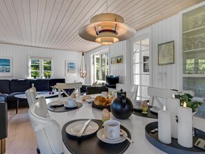 Ein modernes Wohnzimmer mit Essbereich, Holzboden und großen Fenstern. An der Wand hängt eine Karte.