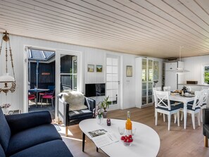 Ein großzügiger Wohnbereich mit Sofa, Esstisch mit Stühlen, Küchenzeile und einem großen Fenster.