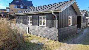 Une maison en bois à deux étages, avec un toit en pente, de grandes fenêtres et un chiffre « 6 » bien visible sur le côté.