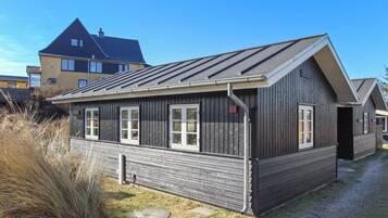A two-story wooden house with a sloped roof, large windows, and a visible number '6' on the side.