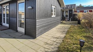 Un bâtiment moderne à l’extérieur sombre, doté de grandes fenêtres et d’un patio couvert.