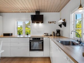 Eine moderne Küche mit weißen Schränken, einem Backofen, einem Geschirrspüler und einer Kaffeestation.