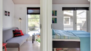 Une chambre à coucher avec un lit, un canapé, une petite table et une plante en pot.